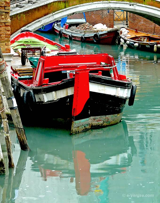 barque et son reflet au milieu des gouttes de pluie sur le rio du Mondo Novo, en face de l'église de Santa Maria Formosa à Venise