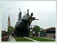 Le sous-marin Enrico Dandolo. Construit en 1967 et mis à la retraite en 1999, d'une longueur de 46,20 mètres et d'une largeur de 4,30, pour un poids total de 524 tonnes (581 tonnes en immersion). Au fond, le Campanile de San Francesco de la Vigna.
